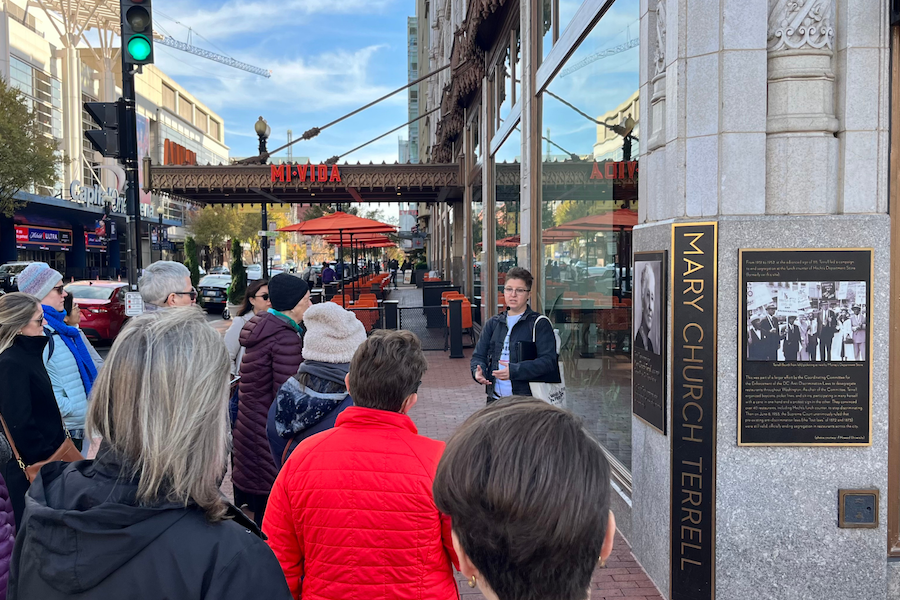 A tour guide speaks to a group outside of a historic building in Downtown DC. 