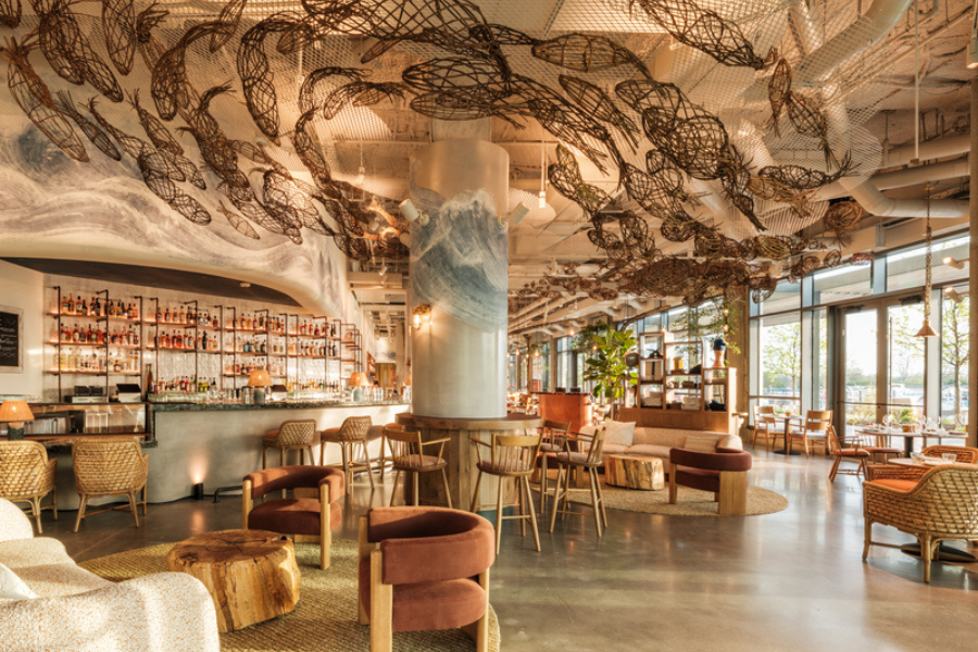 A stylish restaurant in Washington, DC with floor-to-ceiling windows, artistic ceiling sculptures, and cozy natural-fiber furnishings.