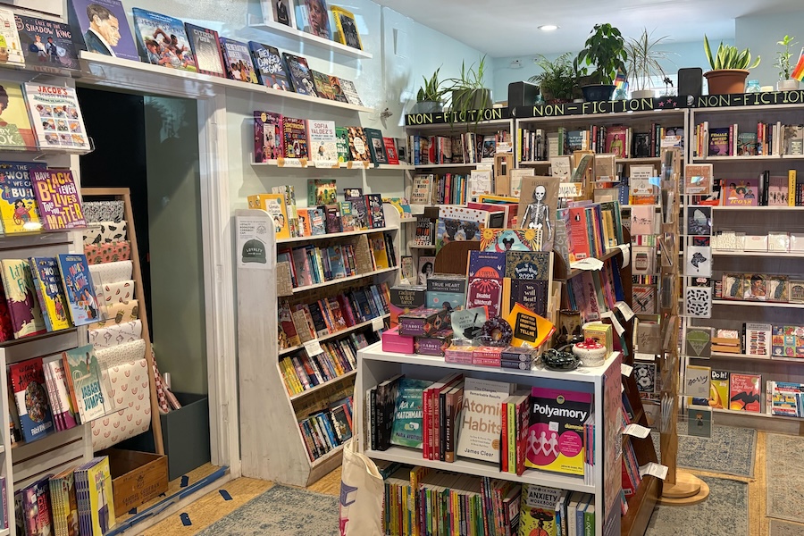 The interior of Loyalty Bookstores featuring colorful bookshelves filled with diverse titles and plants on top.