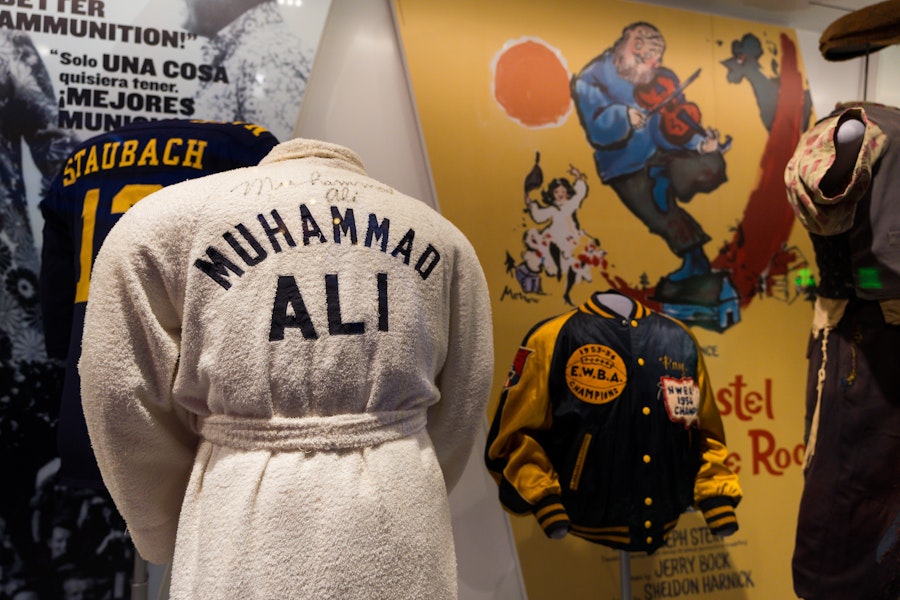 A white boxing robe with “Muhammad Ali” on the back displayed alongside sports memorabilia.
