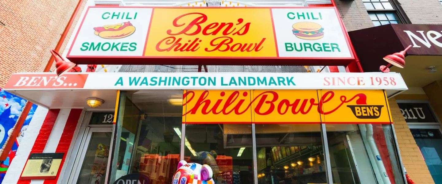 The iconic storefront of Ben's Chili Bowl in Washington, D.C., featuring vibrant red, yellow, and white signage that reads "Ben's Chili Bowl, A Washington Landmark Since 1958."