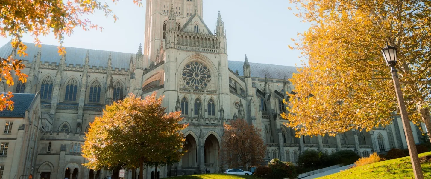 The towers and flying buttresses of Washington National Cathedral stand tall against a bright blue sky.