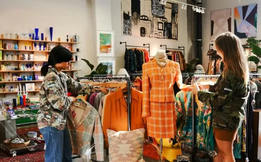 Two customers explore a well-curated vintage shop filled with unique fashion and home decor items.