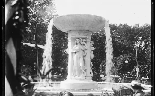 Historic photo of the Dupont Circle Fountain with sculpted figures and cascading water, surrounded by trees and people.