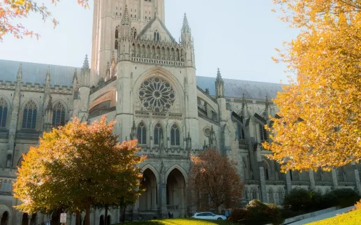 The towers and flying buttresses of Washington National Cathedral stand tall against a bright blue sky.