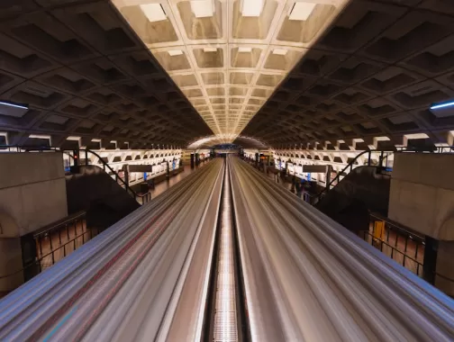 A long-exposure shot captures the motion of a train at Metro Center station in Washington, DC.