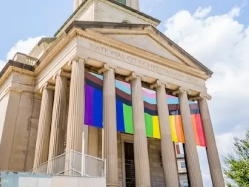 The columns of a historic church decorated with LGBTQIA+ flags.