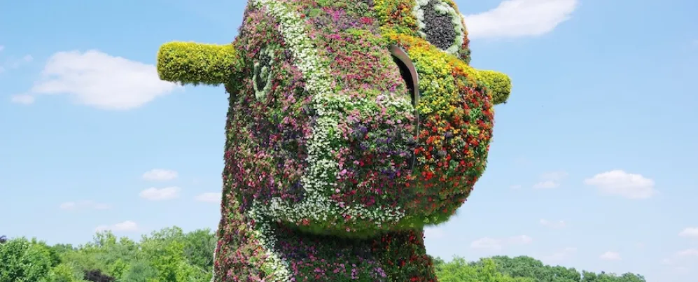 Jeff Koons’s “Split-Rocker” is a massive floral sculpture shaped like a rocking horse head, covered in colorful blooming plants.