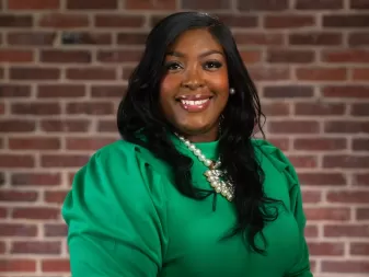 A woman in a bright green blouse smiles for a professional portrait. 