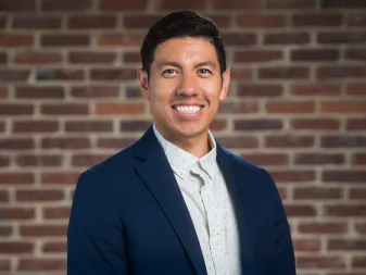 headshot_aaron-chavez-in-blue-blazer-against-brick-wall_ddc
